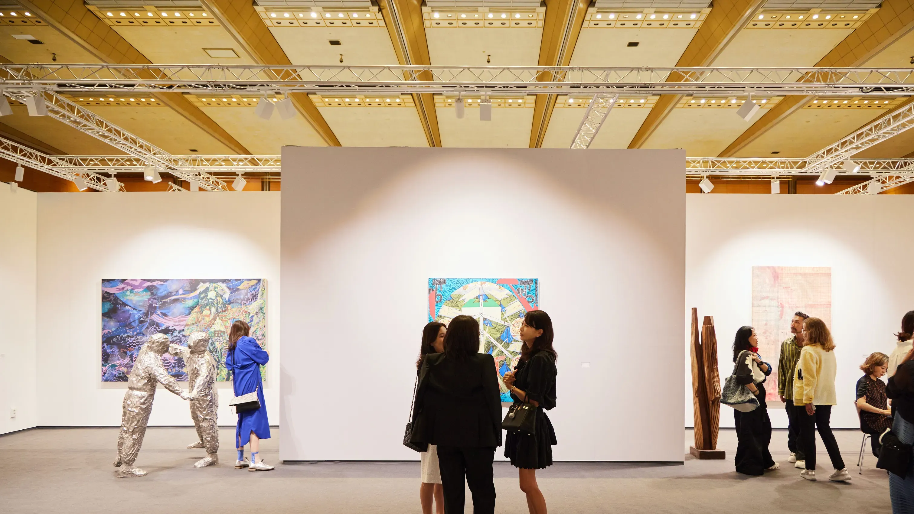 Three visitors standing in front of a Gabrielle May artwork in a gallery