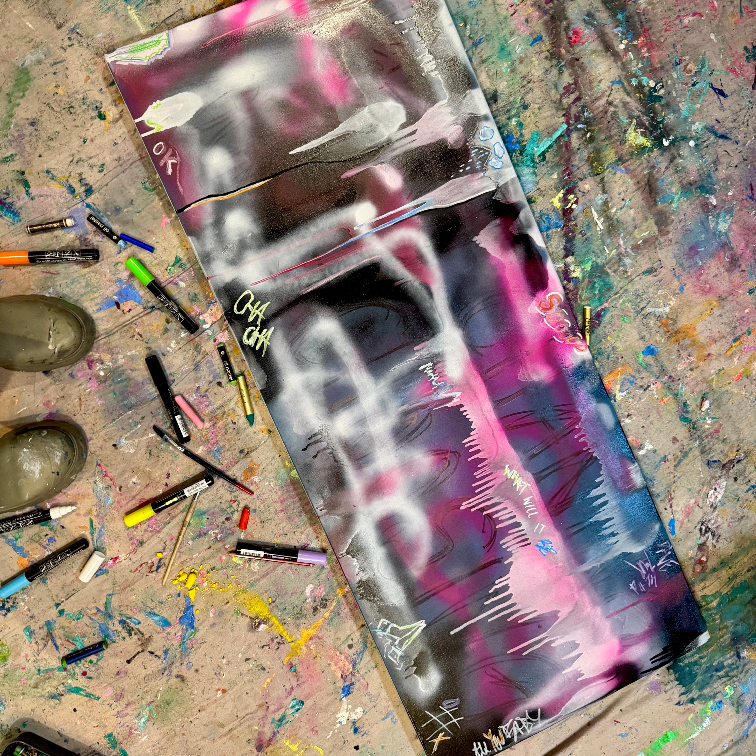 Colourful abstract painting in progress on the studio floor surrounded by art supplies